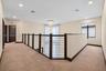 Landing area featuring neutral carpeting, a dark-toned railing with horizontal metal balusters, a multi-tiered spiral chandelier, and solid-core panel