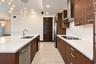 Modern kitchen featuring flat-panel wood-finish cabinetry, white quartz countertops, stainless steel appliances, and multi-light pendant fixtures