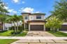 Two-story exterior featuring a contemporary facade, multi-tonal stucco finish, tile roof, multi-car garage, and a paver driveway with turf accents