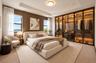 Bedroom featuring a tray ceiling, recessed lighting, wood-paneled accent wall, and floor-to-ceiling glass-front wardrobes with integrated interior lig