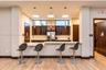 Kitchen area featuring dark wood-finish cabinetry, stone-surface countertops, wood-finish flooring, clerestory windows, and three minimalist pendant l