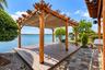 Custom wood pergola featuring a retractable canvas canopy, composite deck platform, irregular stone hardscaping, and built-in outdoor counter