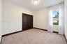 Neutral-toned carpeted flooring, dark-finish paneled closet doors, contrasting dark trim, and a flush-mount ceiling fixture