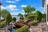 Landscaped backyard featuring a stone water feature, a wooden arched footbridge, flagstone hardscaping, and mature sculpted shrubbery