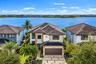 Two-story exterior featuring a hip roof, multi-pane glass entry door, paver driveway with integrated turf grid, and waterfront positioning