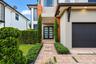 Contemporary two-story exterior featuring a paver walkway with turf inlay, double glass-paneled entry doors, and a multi-section garage door