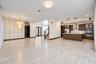 Open-concept interior featuring large-format tile flooring, wood-finish cabinetry, built-in stainless steel appliances, tiered crystal-style chandelie
