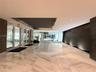 Spacious lobby featuring polished stone flooring in a geometric pattern, an expansive dark-toned accent water wall, recessed ceiling detailing, and gl
