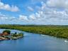 Waterfront aerial perspective featuring a canal, dense vegetation, and a distant cityscape skyline