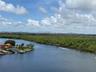 Waterfront setting featuring a wide canal, mature mangrove coastline, and a distant cityscape horizon