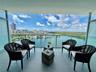 Private balcony featuring large-format tile flooring and a glass railing enclosure, showcasing expansive water and coastal horizon scenery