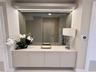 Built-in floating cabinetry featuring a solid surface countertop, expansive wall-to-wall mirror, and integrated LED accent lighting