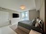 Floor-to-ceiling windows with water backdrop, polished tile flooring, flush-mount lighting, and neutral wall tones