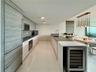 Kitchen featuring flat-panel wood-finish cabinetry, stainless steel built-in refrigerator, integrated wine cooler, stone-surface countertops, and mult