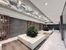 Lobby featuring stone tile flooring, geometric wood wall screens, expansive linear ceiling lighting, and built-in rectangular planters