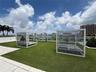 Rooftop terrace featuring synthetic turf, glass panel railings, and white metal louvered privacy structures