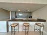 Kitchen featuring wood-finish cabinetry, integrated appliances, a waterfall-edge peninsula with a dark countertop, and polished tile flooring