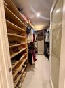Walk-in closet featuring extensive built-in shelving, integrated dresser drawers, hanging rods, and large-format tile flooring