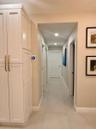 Tall, shaker-style built-in cabinetry with brass hardware, large-format neutral floor tile, recessed ceiling lighting, and a smart thermostat