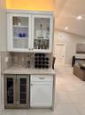 Built-in wet bar featuring white cabinetry, glass-front upper displays, stone-finish countertops, and an integrated under-counter wine refrigerator