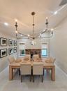 Vaulted ceiling, multi-arm metal chandelier, exposed brick fireplace, and large-format tile flooring