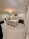 Neutral-toned large format tile flooring, crystal chandelier light fixture, recessed ceiling lighting, and window with woven shade