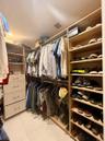 Walk-in closet featuring custom light-finish wood cabinetry, multiple tiers of hanging storage, built-in shelving for footwear, and a four-drawer dres