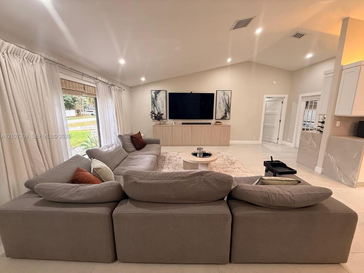 Vaulted ceilings, large-format tile flooring, recessed lighting, custom built-in cabinetry, and sliding glass door