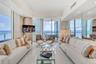 Floor-to-ceiling glass walls, polished stone flooring, recessed lighting, mirrored wall accents, and a private balcony
