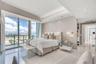 Floor-to-ceiling glass sliding doors, tray ceilings with recessed lighting, polished porcelain tile flooring, textured wall finishes, and a dedicated 