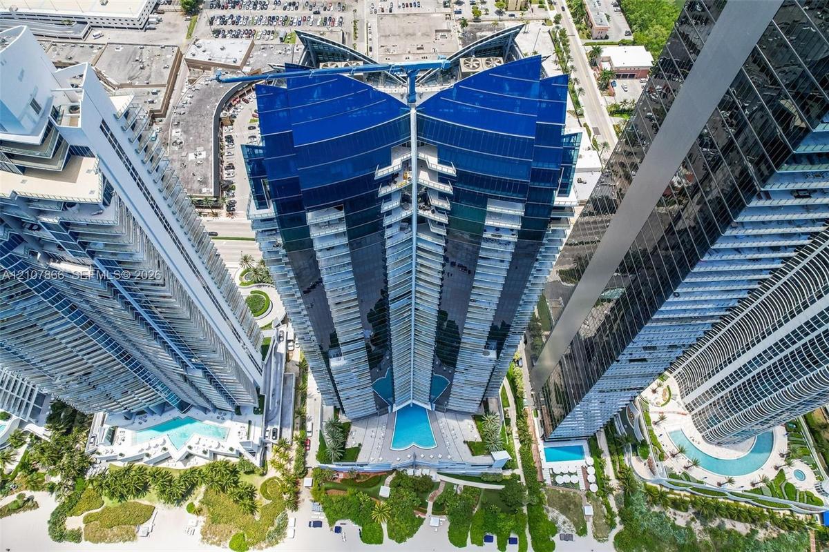 High-rise building featuring a glass facade, tiered balconies, and an outdoor swimming pool with surrounding landscaping