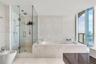 Bathroom featuring a built-in soaking tub, glass-enclosed walk-in shower with a rainfall showerhead, stone-tile flooring, textured stone-accent wall, 