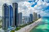 High-rise architecture featuring blue-tinted glass curtain walls and wrap-around balconies, situated directly on the Atlantic coastline with immediate
