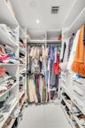 Custom walk-in closet featuring extensive white built-in cabinetry, tiered shelving, integrated hanging rods, recessed lighting, and large-format tile