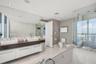 Floating double vanity with dual vessel sinks, full-width wall mirror, glass-enclosed shower, soaking tub, and stone tile flooring