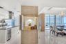 Stacked stone accent wall with a recessed display niche, white high-gloss cabinetry, stainless steel range hood, built-in wine refrigerator, and floor