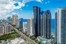 High-rise residential tower featuring glass-curtain exterior walls, tiered balconies, integrated pool deck, and coastal positioning
