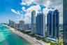 Coastal high-rise buildings featuring floor-to-ceiling glass facades, prominent balconies, and direct oceanfront positioning