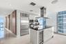 Modern kitchen featuring high-gloss cabinetry, stainless steel professional-grade appliances, a central island with a built-in wine refrigerator, a st