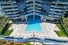High-rise pool terrace featuring a geometric swimming pool, paved sundeck, glass-railed balconies, and landscaped grounds