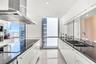 Contemporary kitchen featuring flat-panel white cabinetry, contrasting black stone countertops, an integrated stainless steel range hood, double under