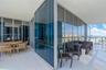 Wraparound balcony featuring floor-to-ceiling glass paneling, reflective window glazing, and large-format tile flooring