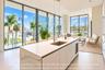 Kitchen island with stone-surface countertop, under-mount stainless steel sink, built-in beverage refrigerator, floor-to-ceiling glass panel walls, an