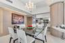 Formal dining area featuring a tiered crystal chandelier, wood-finish wall paneling, curved built-in cabinetry, and white polished flooring
