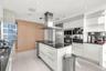 Contemporary kitchen featuring high-gloss white cabinetry, polished stone countertops, stainless steel professional-grade appliances, a central island