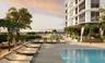 Outdoor terrace featuring a swimming pool, stone-finish decking, tiered landscaping, and pergola structures