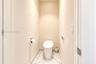 Enclosed water closet featuring a one-piece skirted toilet, large-format stone-finish floor tile, and brushed metal hardware