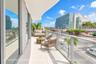 Expansive curved balcony with large-format floor tile, glass panel railing, and floor-to-ceiling sliding glass doors