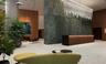 Lobby featuring stone wall cladding, custom crystal chandelier, wood-veneer desk with integrated lighting, and wood-finish paneling