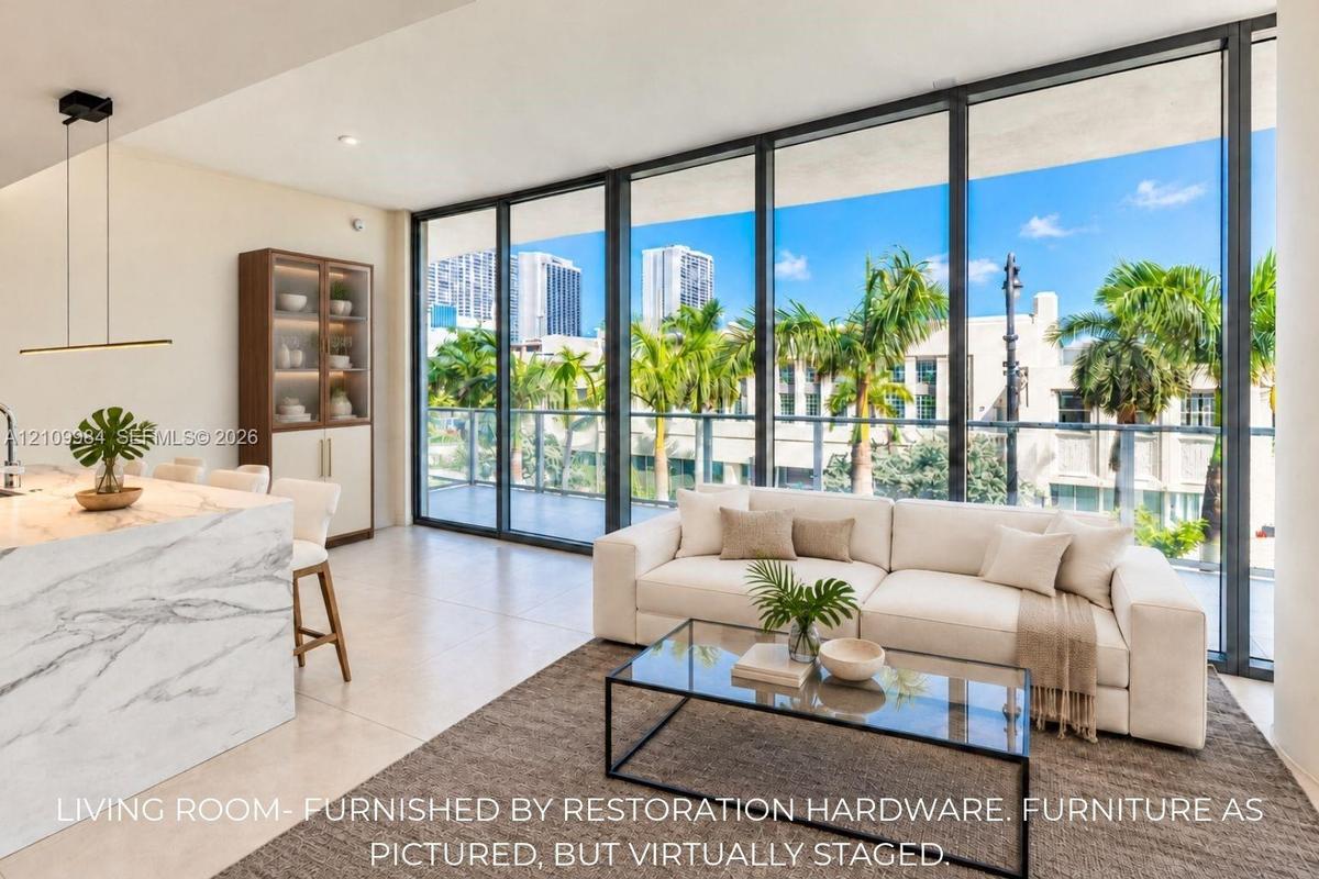 Floor-to-ceiling glass wall, expansive private balcony, stone-finish kitchen island with waterfall edge, built-in cabinetry, and large-format tile flo